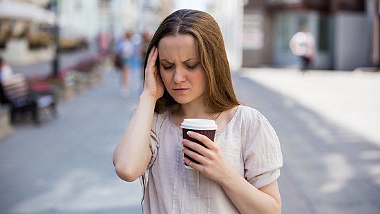 woman with headache drinking coffee