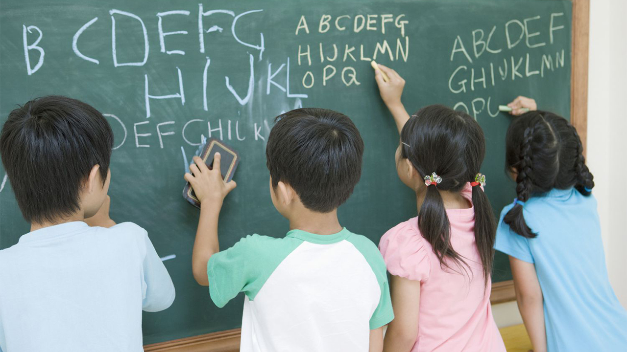 Enseignement de l'anglais au Japon, les enfants asiatiques écrivent l'alphabet au tableau noir